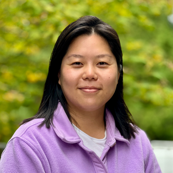 Asian women with dark, brown hair and eyes. Wearing light purple fleece jacket