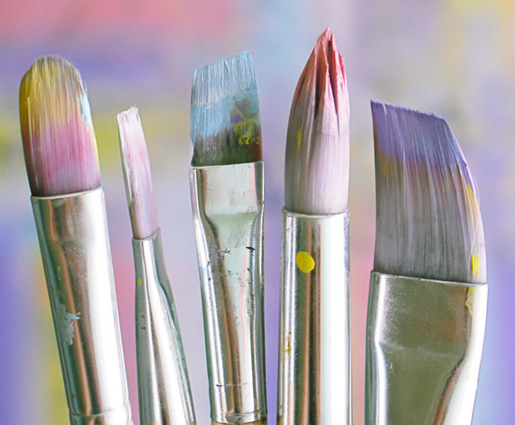 Set of paintbrushes with pastel paint on the tips.