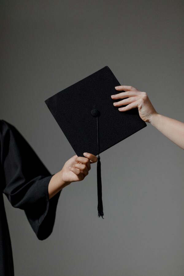 hands passing a university graduation cap