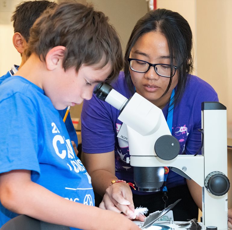 Nhu Ly helps student with feather.