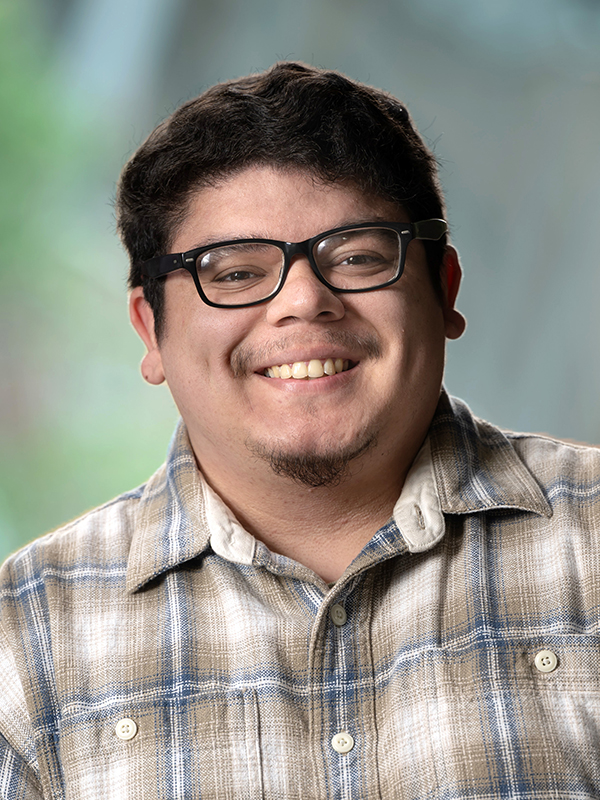 Close-up portrait of Luis Rodriguez wearing glasses and a blue and tan flannel shirt.