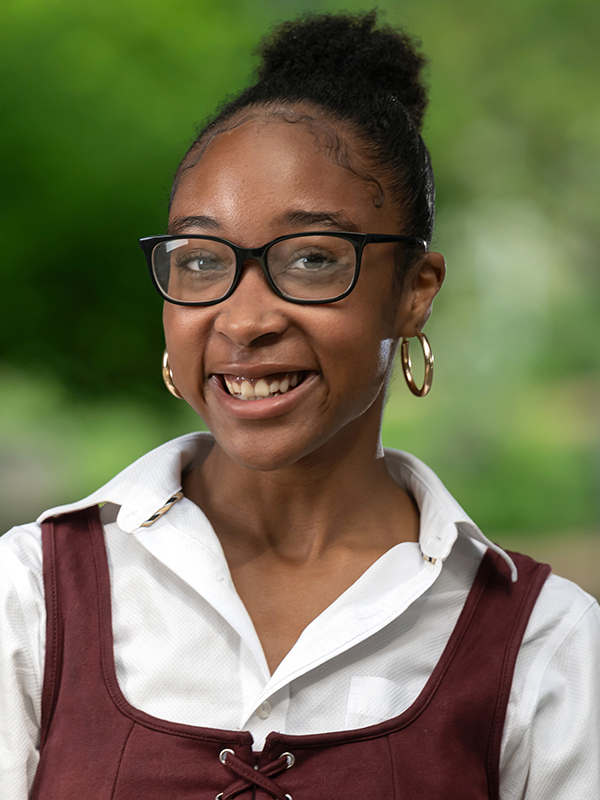 Close-up portrait of Mariyah Hicks wearing glasses and a maroon and white top.