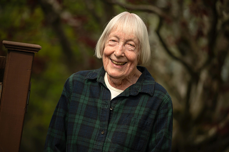 Environmental portrait of Anne Loustau on her property wearing a blue and green flannel.