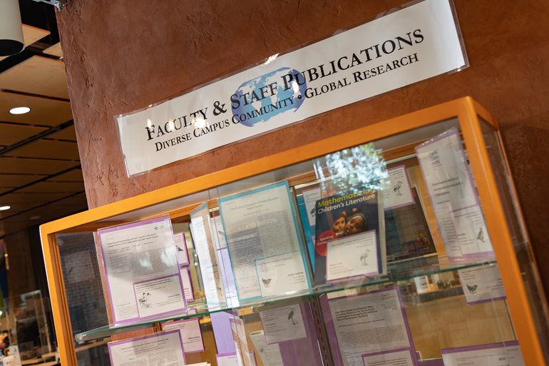 Banner with Faculty and Staff publications above a book shelf