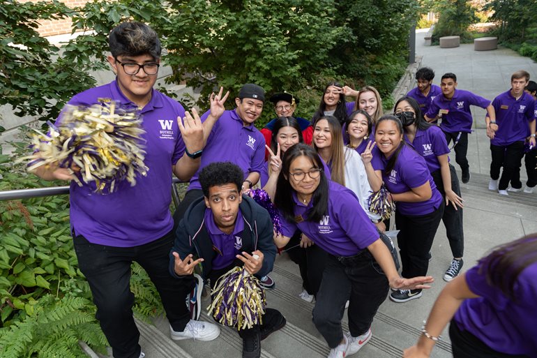 Group of students in W purple shirts surrounding the Chacellor