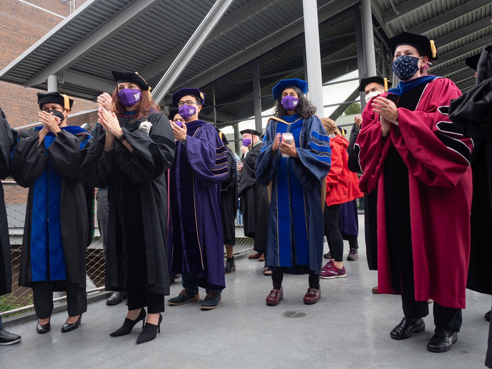 Faculty standing and clapping for students