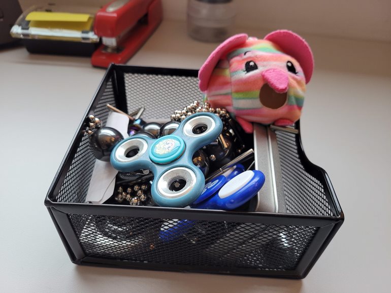 Box of toys including magnets and fidget spinners on Erik Echols desk