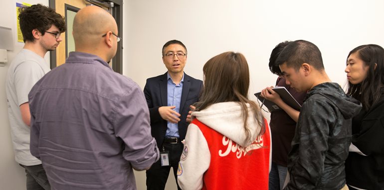 Enzhou Wang discusses project with students.