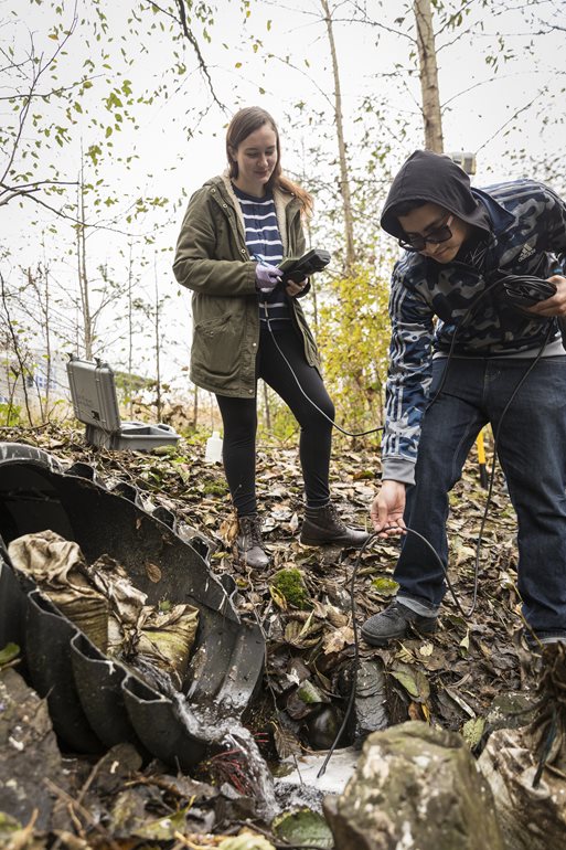 Sampling water from stormwater pipe.