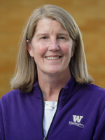 E&M Interim Chair and Professor Dr. Linda Simonsen with ash blond hair, purple chair on smiling at the camera. In from of a golden wall.