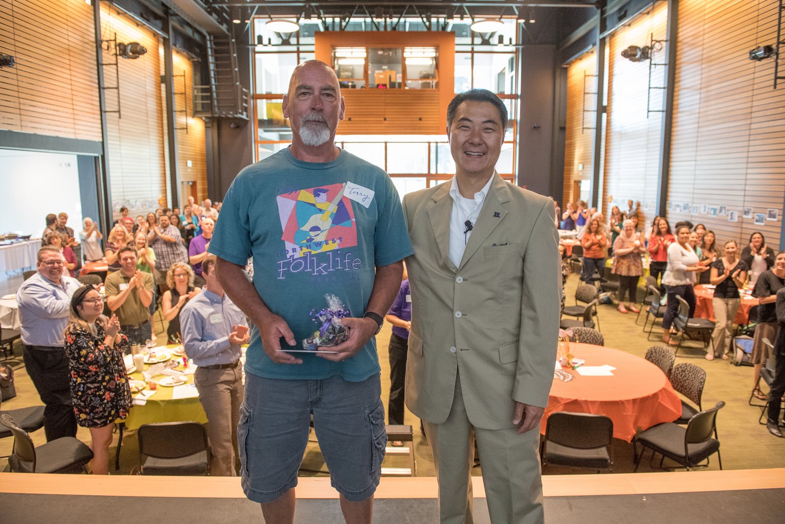 Sergeant Terry Rauch and Chancellor Wolf Yeigh on stage in front of a crowd giving a standing ovation.