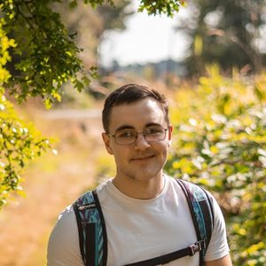 Profile image of student Luke Scott smiling in a bright field. 