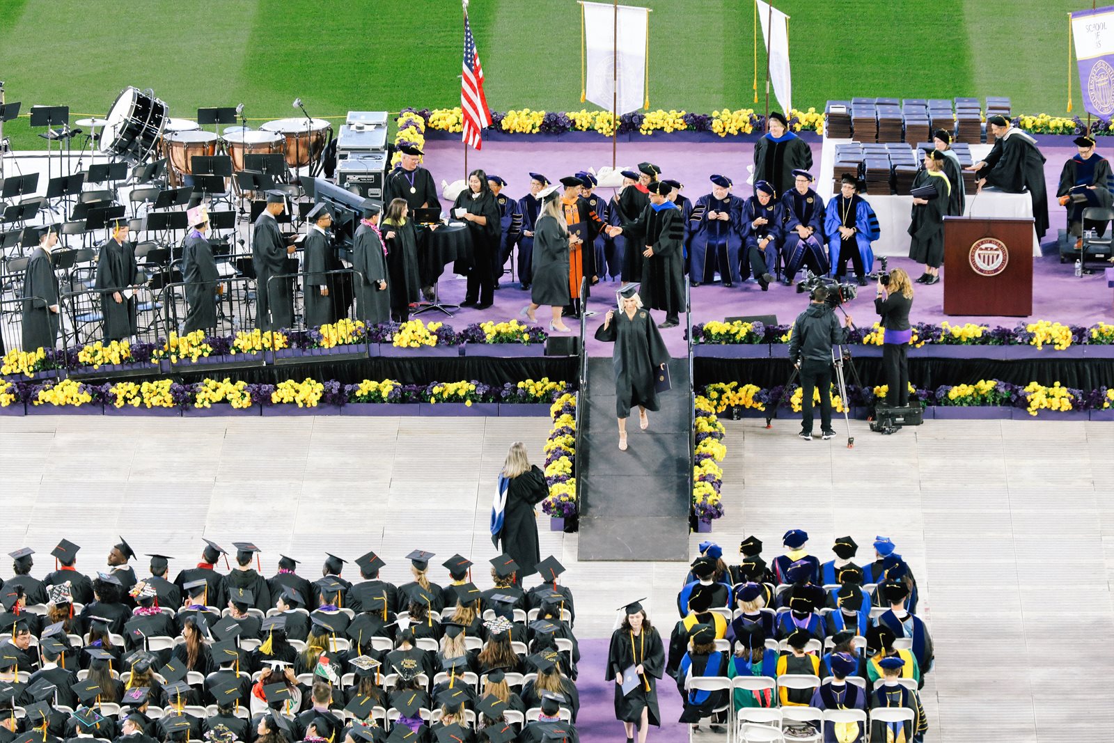 Grads crossing stage with diploma